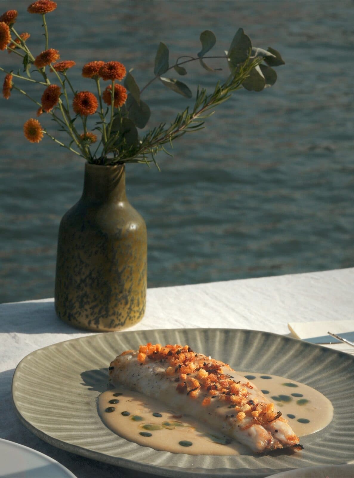 A fish fillet plated at TEJÁ, sauce spooned around it.