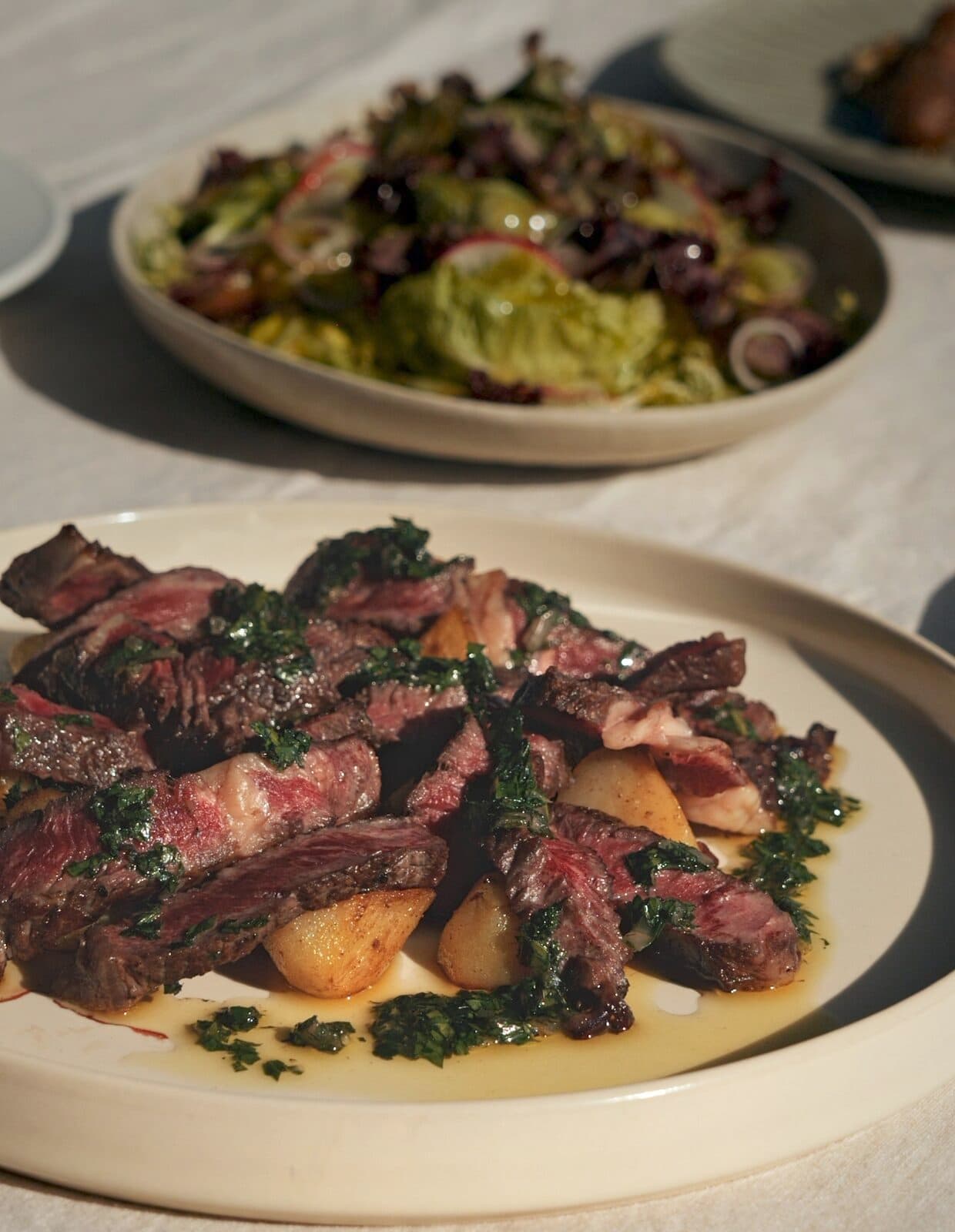 Sliced steak with greens and potatoes on a plate at TEJÁ.